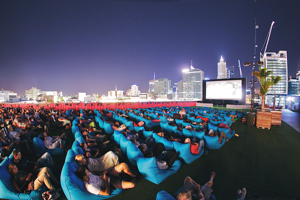 View of audience watching movie on rooftop with City in background